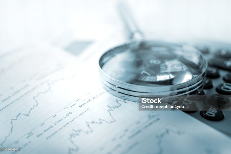 uma lupa em cima de papeis que exibem o volatilidade do mercado