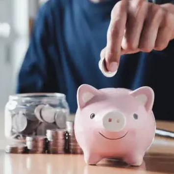 um hoemn colocando moeda no cofrinho que é um porquinho