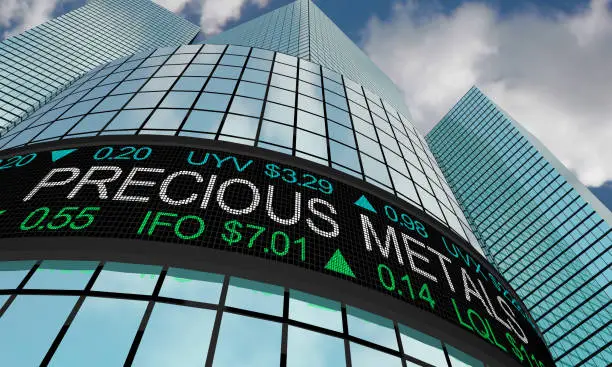 A imagem mostra a fachada de um prédio corporativo moderno, com grandes janelas de vidro espelhado refletindo o céu. Na parte inferior da construção há um painel eletrônico de cotações financeiras, semelhante aos encontrados em bolsas de valores. No letreiro, em destaque, aparece a frase “PRECIOUS METALS” (Metais preciosos), acompanhada de números, siglas e valores em dólares, representando preços e variações de mercado. As setas verdes apontando para cima indicam valorização. O cenário transmite a ideia de mercado financeiro, investimentos internacionais, bolsas de valores e economia global.